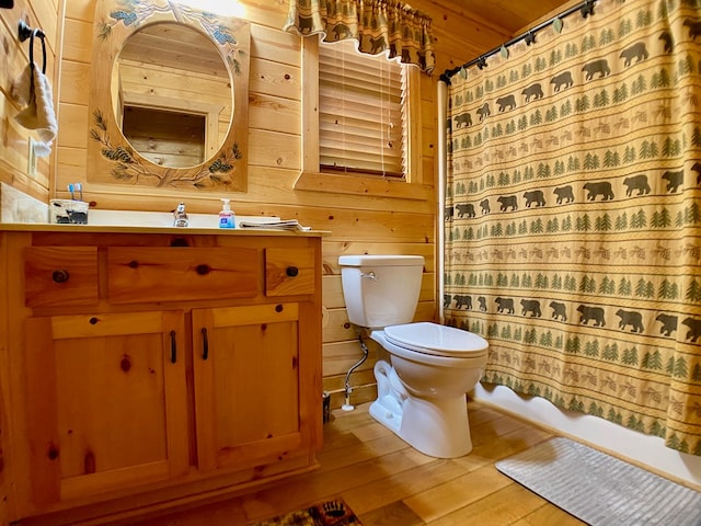 full bathroom featuring toilet, wood walls, wood finished floors, and vanity