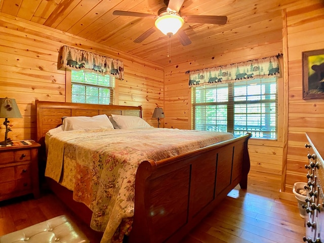 bedroom with wood-type flooring, a ceiling fan, wooden walls, and wooden ceiling