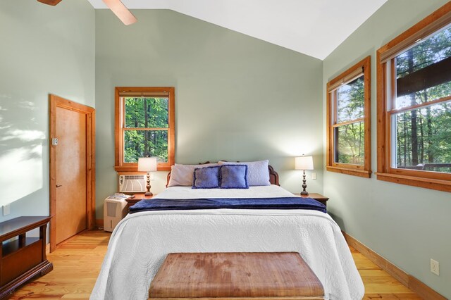 bedroom featuring ceiling fan, high vaulted ceiling, light hardwood / wood-style flooring, and a wall unit AC