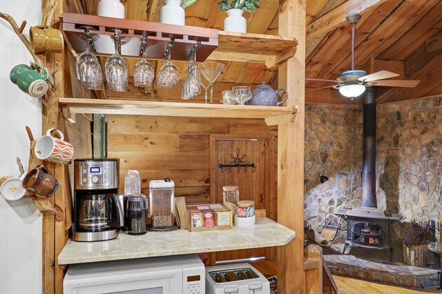 kitchen featuring ceiling fan, washer / clothes dryer, wood walls, and a wood stove