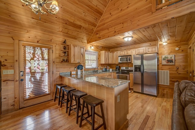 kitchen featuring lofted ceiling, kitchen peninsula, light stone countertops, wood ceiling, and stainless steel appliances