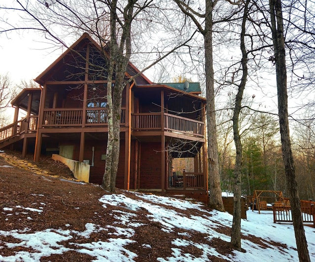 snow covered back of property featuring a sunroom