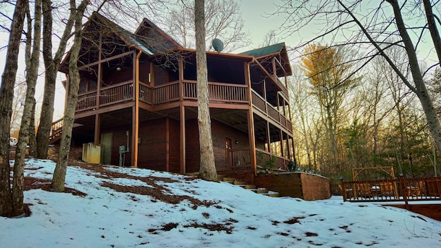 snow covered back of property featuring a balcony