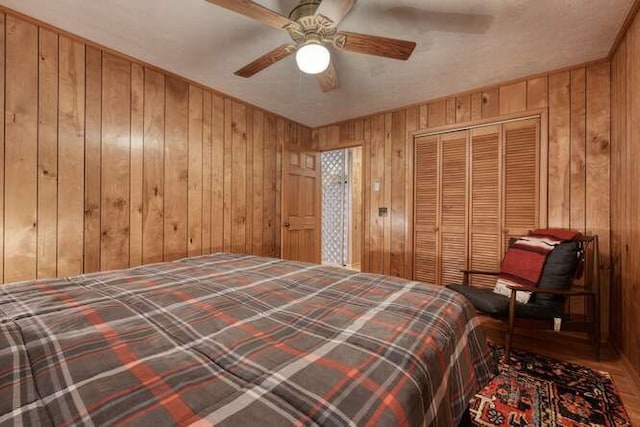 bedroom featuring a closet, wooden walls, and ceiling fan