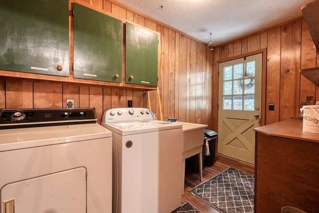 clothes washing area featuring wood finished floors, cabinet space, independent washer and dryer, and wood walls