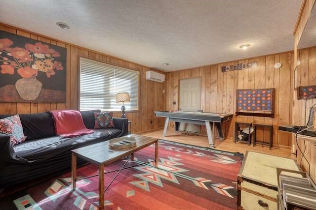 living room with wooden walls, a textured ceiling, a wall unit AC, and wood finished floors