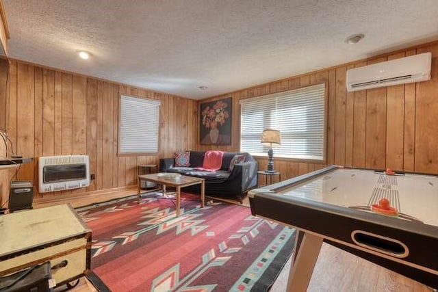 playroom featuring a textured ceiling, heating unit, wood walls, and a wall mounted AC