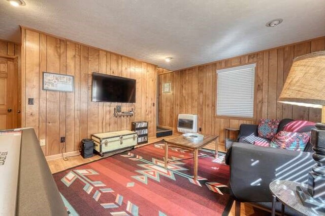 living room with baseboards, heating unit, wood finished floors, and wood walls