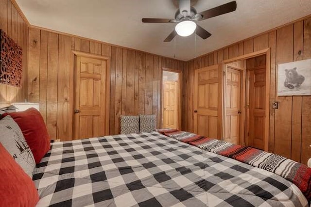 bedroom featuring wooden walls and ceiling fan