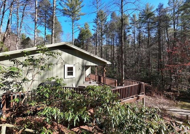 view of side of property with a deck and a forest view