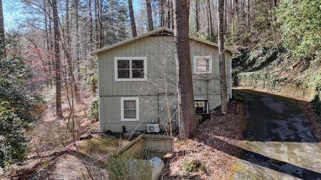 view of side of property featuring a view of trees and driveway