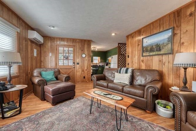 living room with wooden walls, light wood-style flooring, and a wall mounted air conditioner