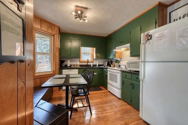 kitchen with white appliances, light wood-style floors, under cabinet range hood, green cabinets, and dark countertops