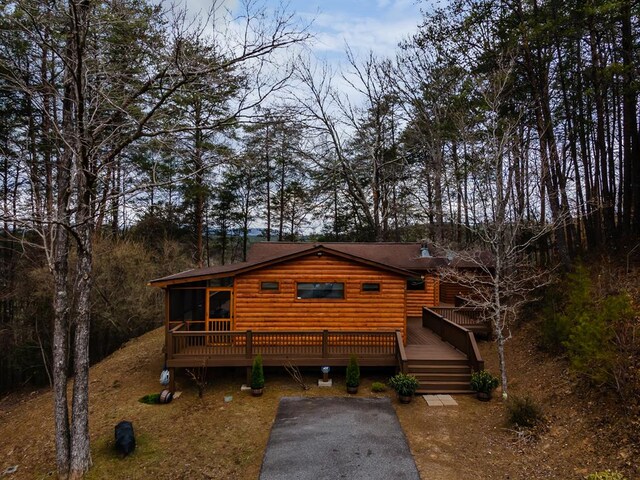 log cabin featuring a sunroom, faux log siding, and a deck