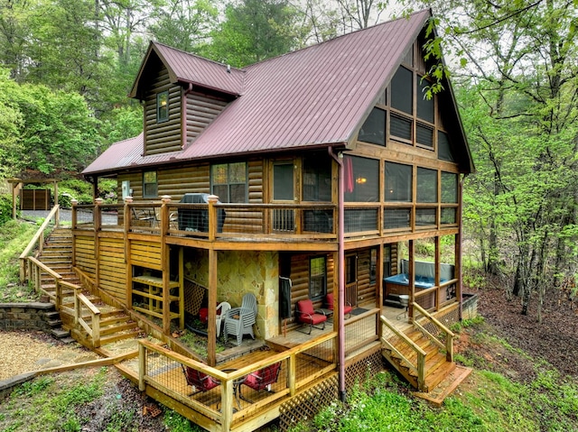 rear view of property featuring stairway, a deck, metal roof, and a sunroom