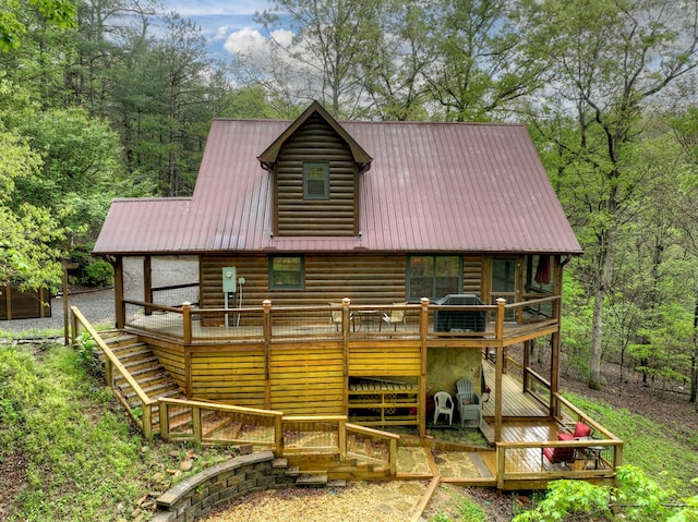 rear view of house featuring log veneer siding, a wooden deck, metal roof, and stairs