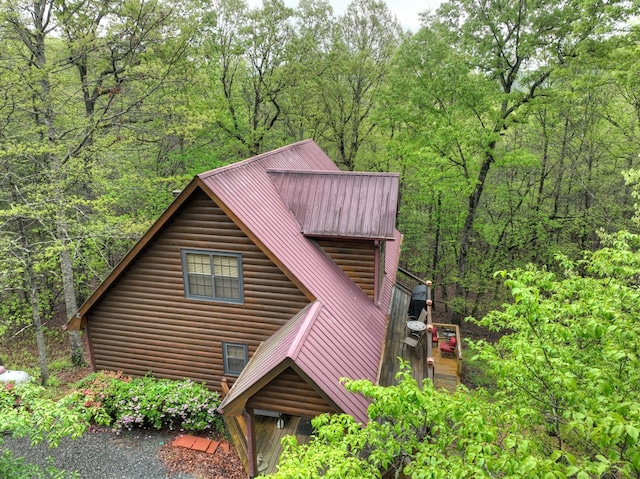 view of front of property with faux log siding, metal roof, and a wooded view
