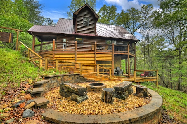 rear view of property featuring an outdoor fire pit, a deck, metal roof, stairway, and faux log siding