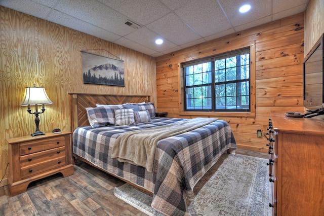 bedroom with wood walls, wood finished floors, a paneled ceiling, and recessed lighting