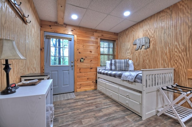 bedroom with wooden walls, wood finished floors, and recessed lighting