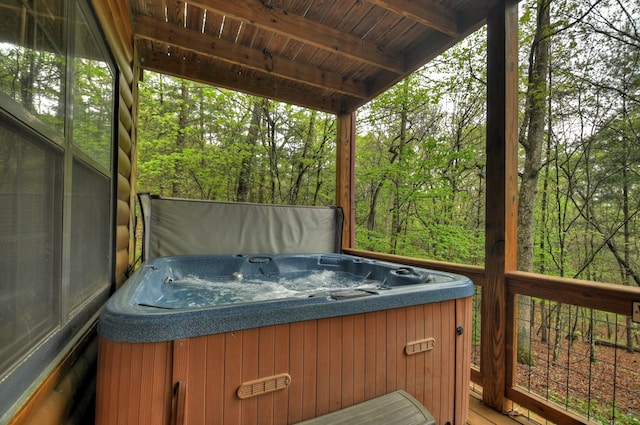 wooden deck with a hot tub and a wooded view