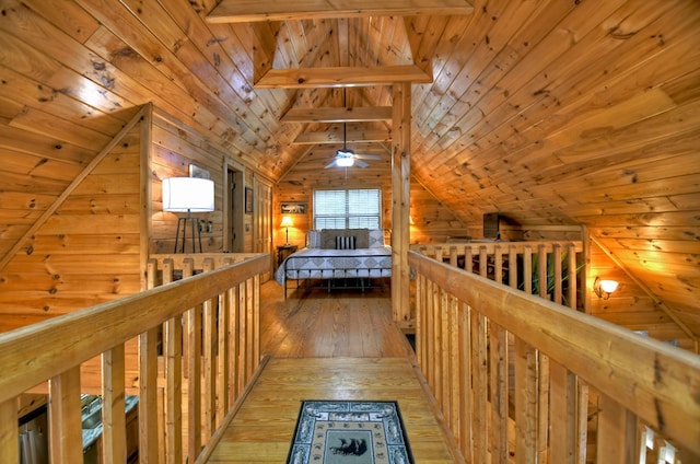 hallway with vaulted ceiling, wooden ceiling, an upstairs landing, light wood-style flooring, and wood walls