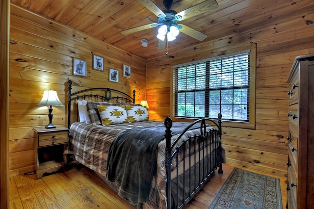 bedroom with wood walls, light wood-type flooring, and wooden ceiling