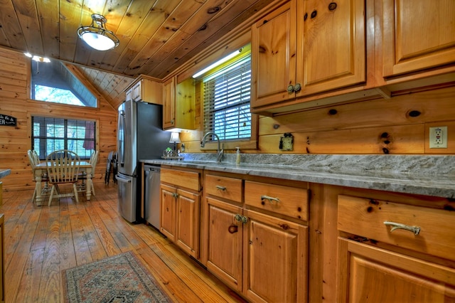 kitchen featuring a sink, wood ceiling, dishwasher, light wood finished floors, and wood walls