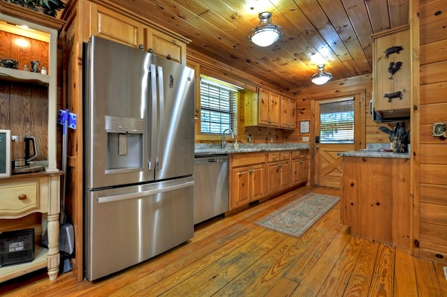 kitchen featuring appliances with stainless steel finishes, light wood finished floors, plenty of natural light, wood ceiling, and light stone counters