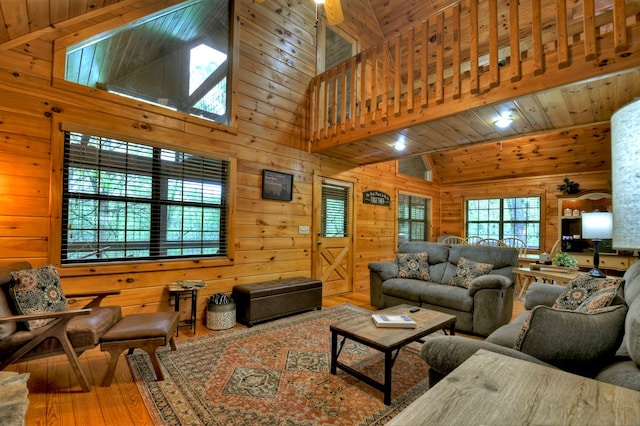 living area with hardwood / wood-style flooring, wooden walls, and high vaulted ceiling