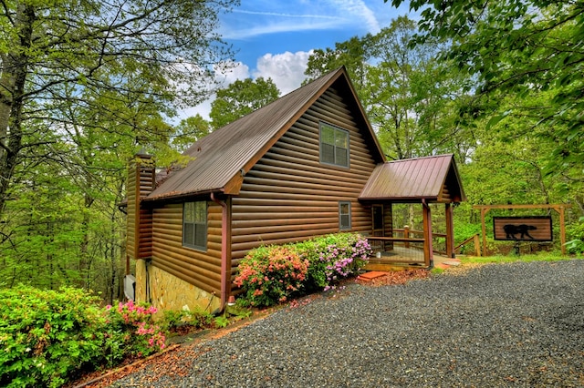 view of property exterior with metal roof, a chimney, and stone siding