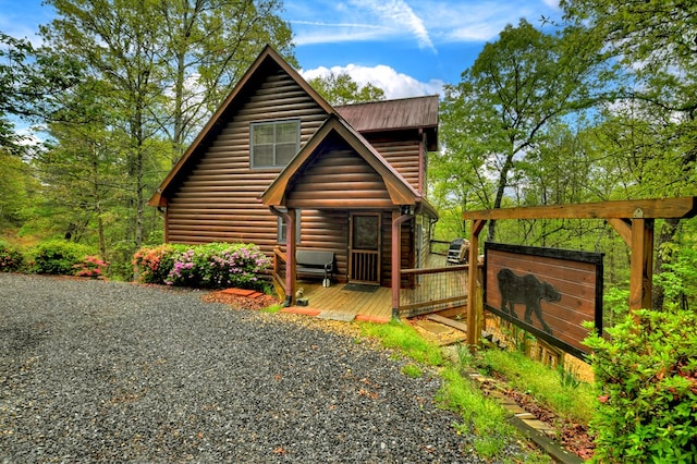 view of front facade with a deck, log veneer siding, and metal roof