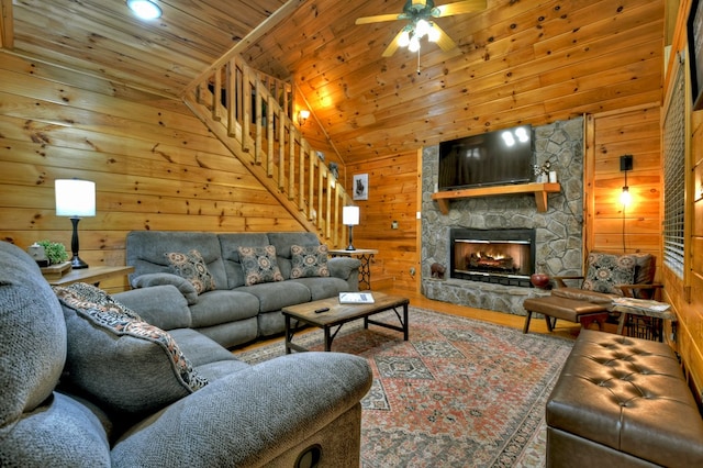 living area with wooden walls, stairs, ceiling fan, wood finished floors, and wooden ceiling