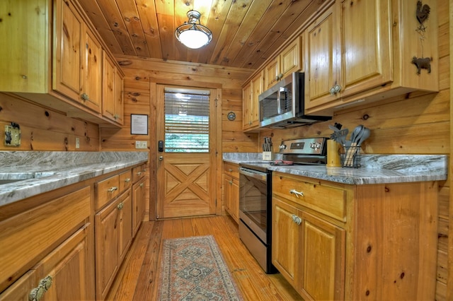 kitchen featuring appliances with stainless steel finishes, wooden walls, light wood-type flooring, wooden ceiling, and brown cabinets