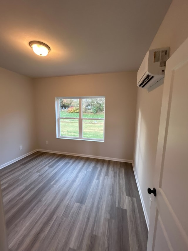 unfurnished room featuring dark wood-type flooring and a wall unit AC