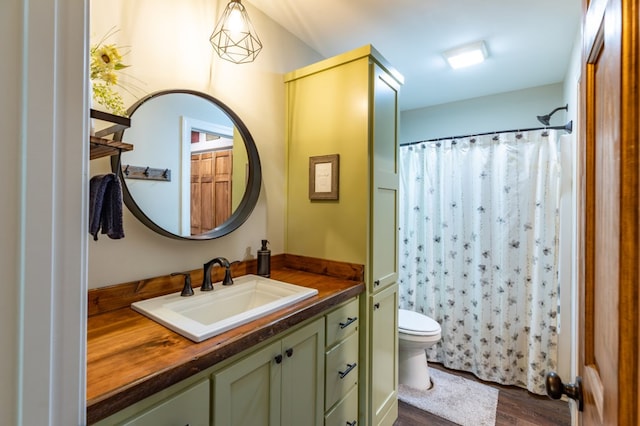 full bath with toilet, a shower with curtain, wood finished floors, and vanity