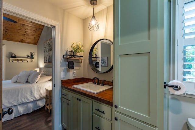 bathroom with vaulted ceiling, ensuite bath, wood finished floors, and vanity