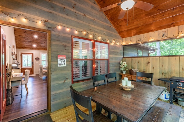 dining area featuring vaulted ceiling, wood finished floors, wood ceiling, and wooden walls