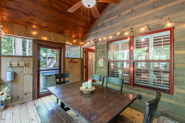 unfurnished dining area with a ceiling fan, wood ceiling, hardwood / wood-style floors, vaulted ceiling, and wood walls