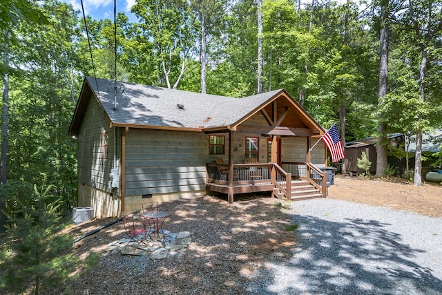 view of front facade featuring a shingled roof, a wooden deck, central AC unit, crawl space, and an outdoor structure