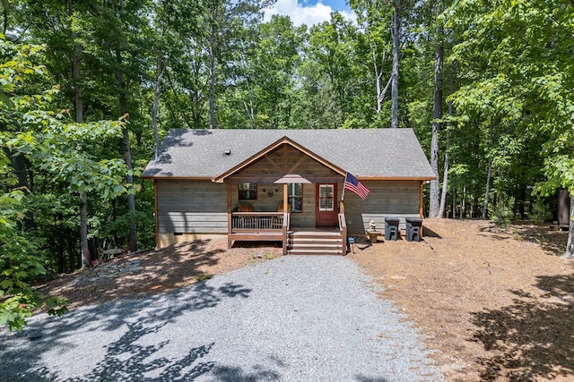 rustic home featuring roof with shingles and a wooded view