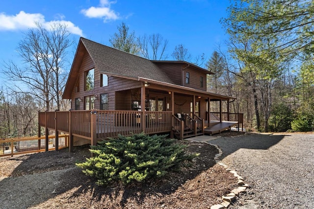 view of side of property featuring a shingled roof and a wooden deck