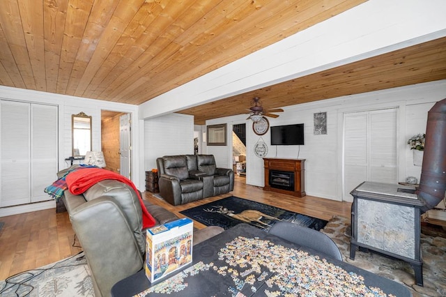 living room with wood walls, wood-type flooring, ceiling fan, and wooden ceiling