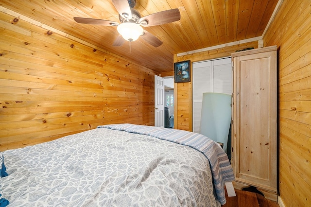 bedroom with ceiling fan, wood-type flooring, wood ceiling, wooden walls, and a closet