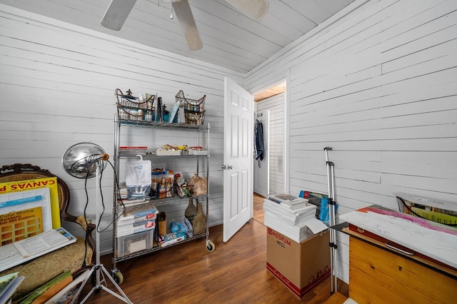 interior space with dark wood-type flooring, ceiling fan, and wood walls