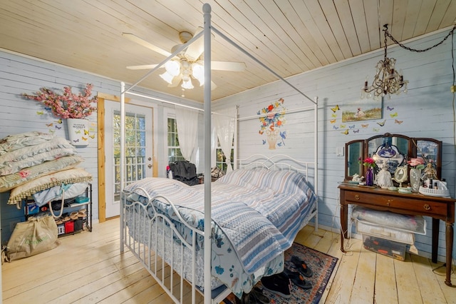 bedroom featuring access to outside, hardwood / wood-style flooring, wooden walls, wooden ceiling, and ceiling fan