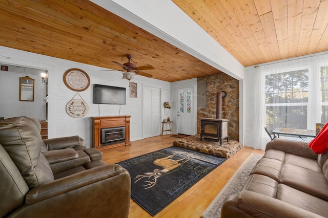 living room featuring wooden ceiling, ceiling fan, a wood stove, and hardwood / wood-style floors