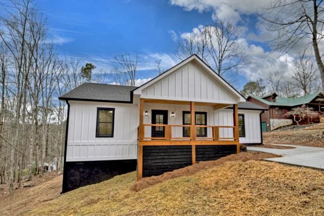 rear view of property featuring covered porch, board and batten siding, and roof with shingles