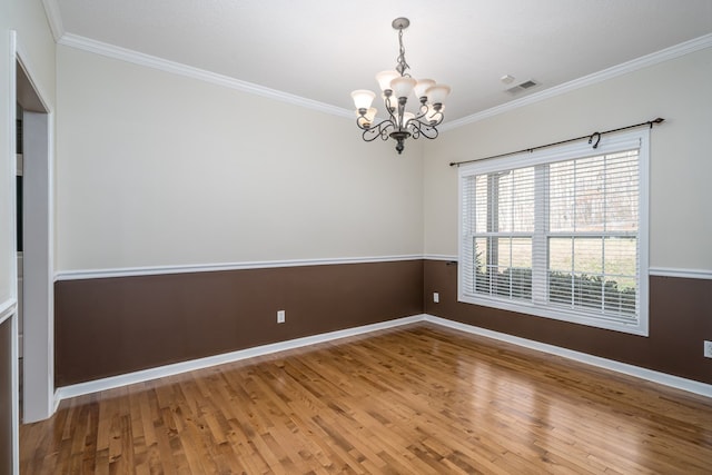 empty room featuring wood-type flooring, ornamental molding, and an inviting chandelier