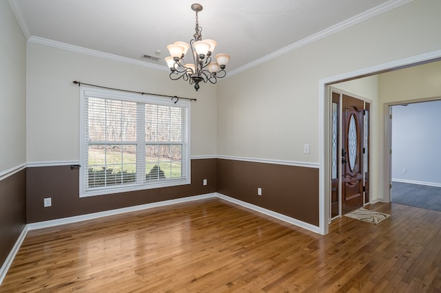 spare room with crown molding, hardwood / wood-style floors, and a notable chandelier